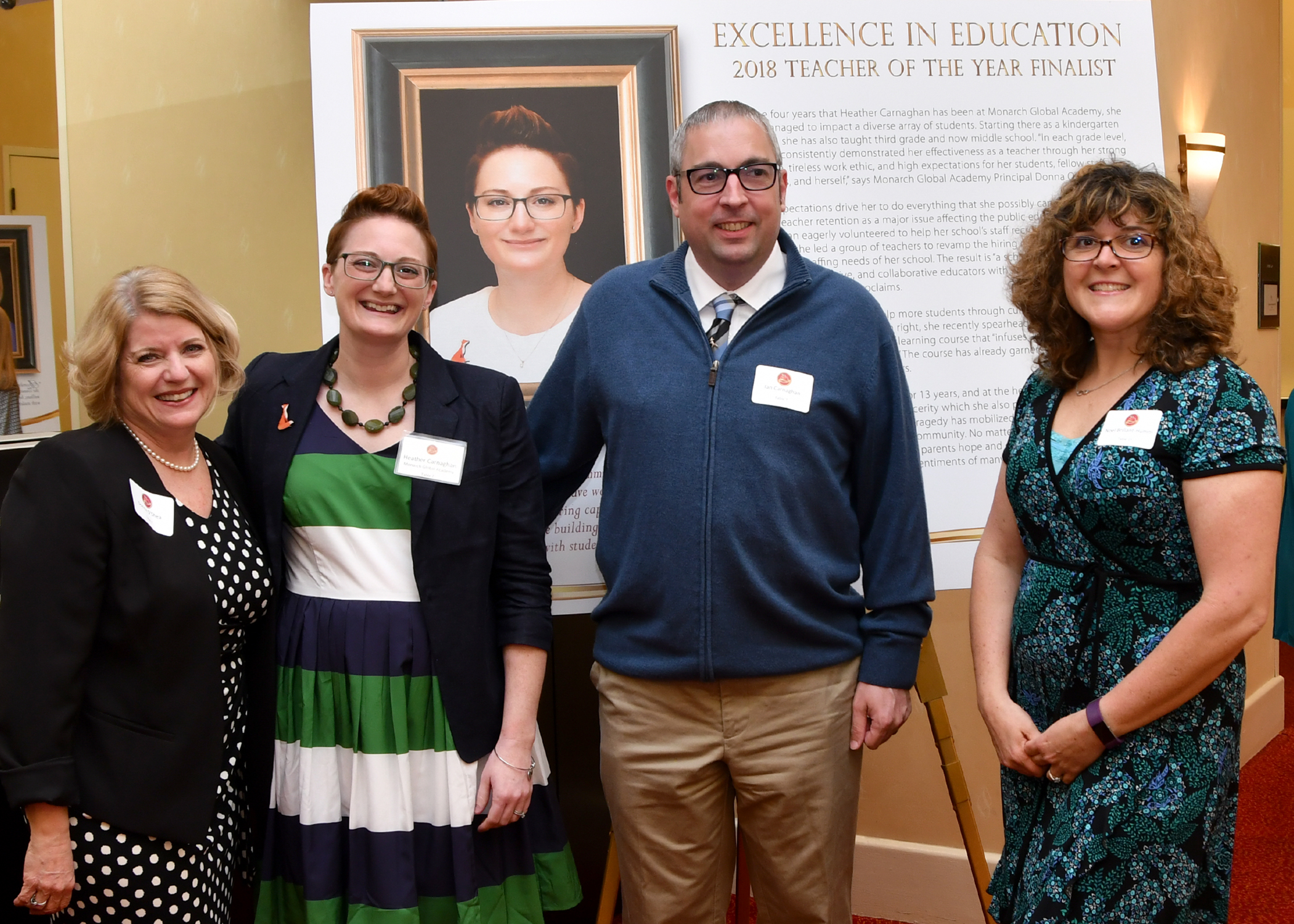 Heather Carnaghan stands with family and friends in front of her celebration poster at the Excellence in Education Event