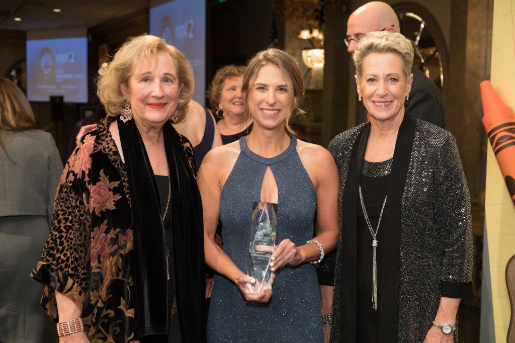 Teacher of the Year Winner Teresa Beilstein with her award standing between two women.